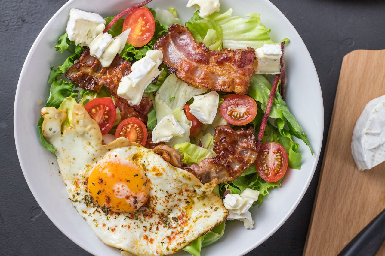Fresh ketogenic salad with bacon, egg, feta, and tomatoes, perfect for healthy eating.
