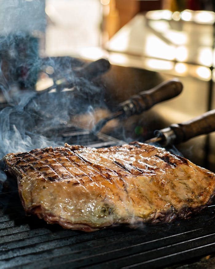 A delicious piece of steak being grilled to perfection on an outdoor barbecue grill, exuding a smoky aroma.